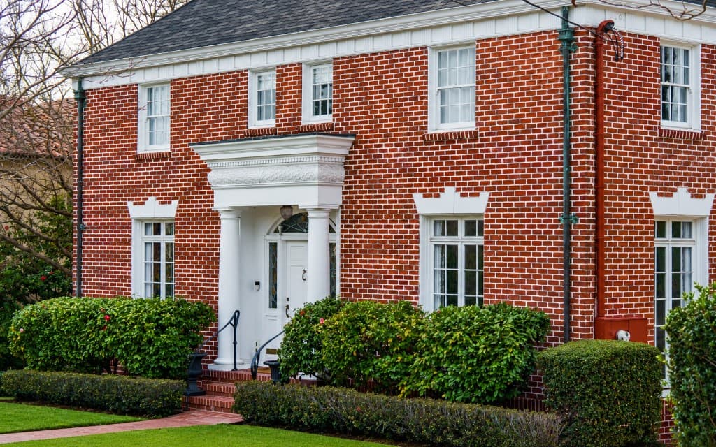 Red brick home with white window trim and a columned entrance.