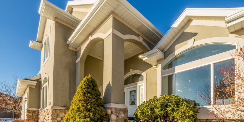 Beige stucco home exterior with decorative columns and white trim.
