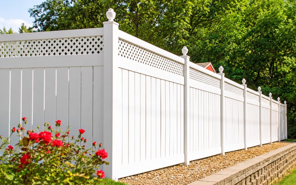 White privacy fence with decorative lattice and red roses.