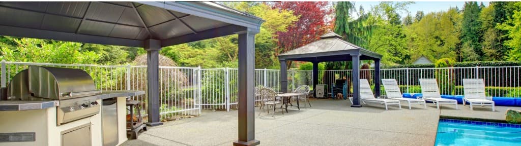Concrete pool deck and outdoor patio with covered seating.