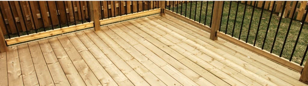 Wooden deck with black metal balusters and a timber privacy fence.