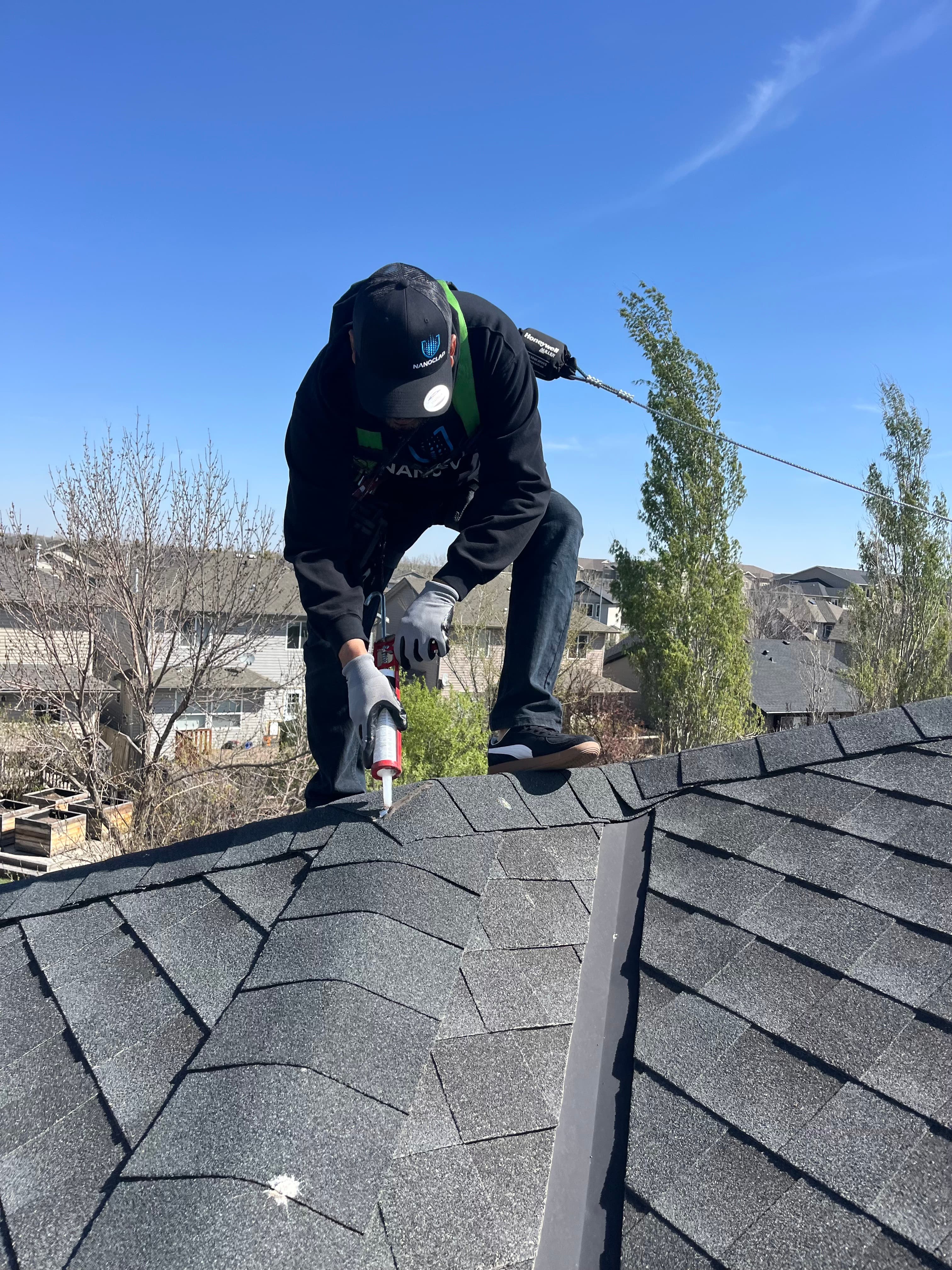Nanoclad technician performing professional application work on an asphalt-shingle roof
