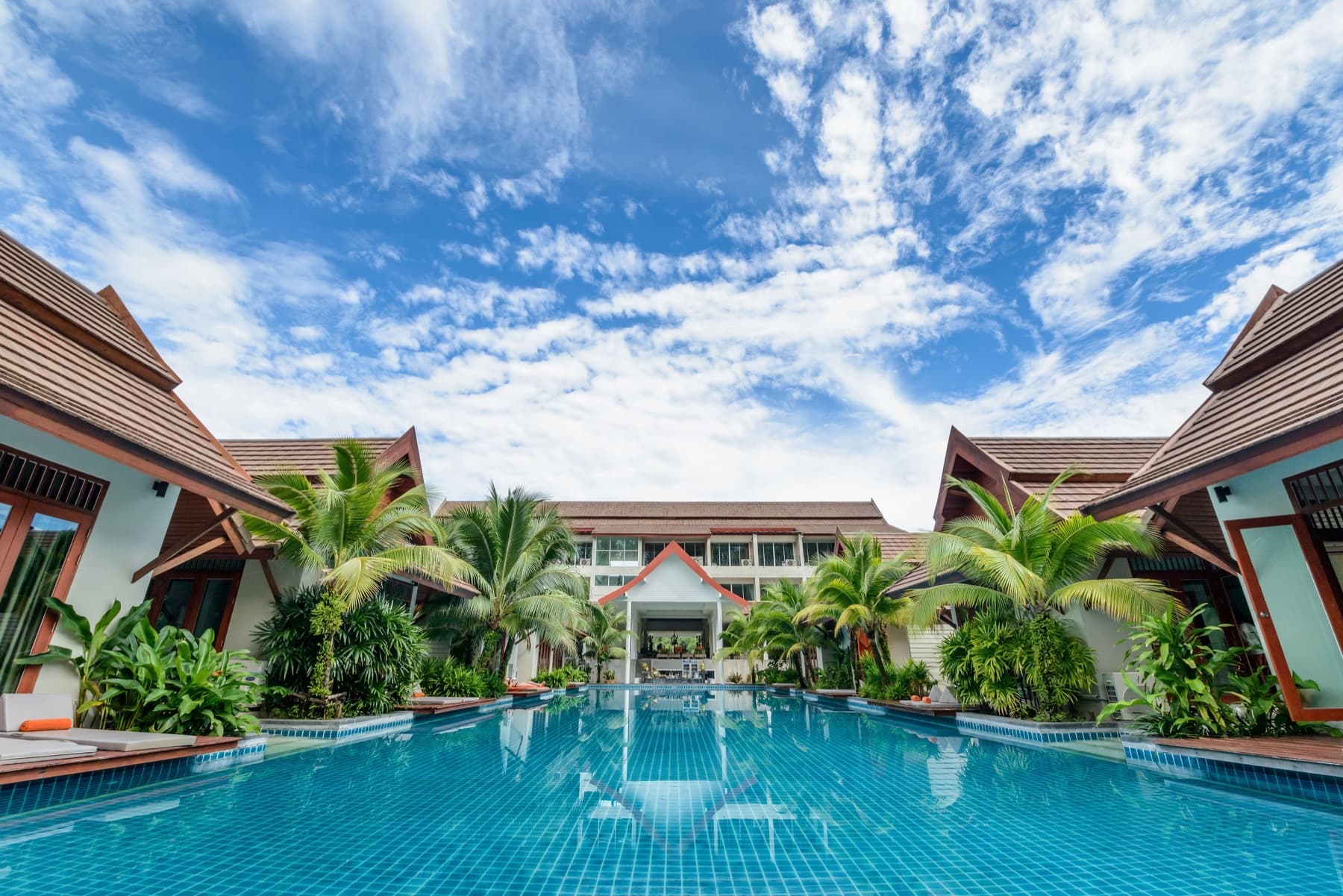 Daylit hotel courtyard with white painted facades, dark wood trim, and a central pool
