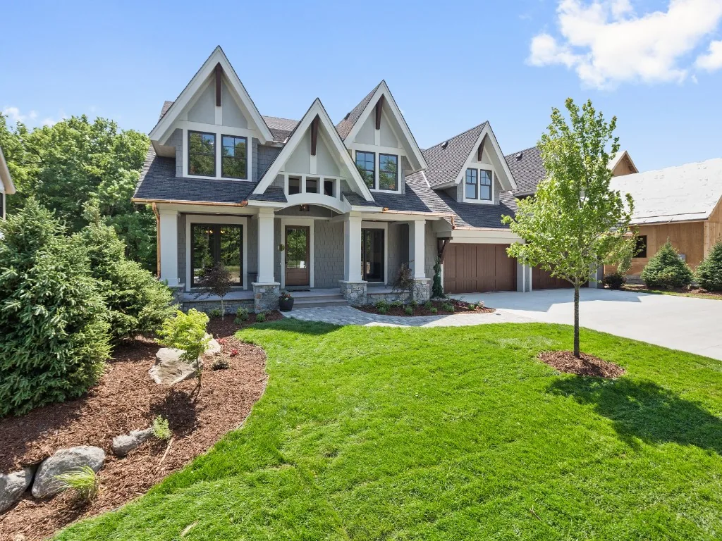 Grey suburban home with asphalt shingle roofing, painted siding, stone accents, and a concrete driveway.